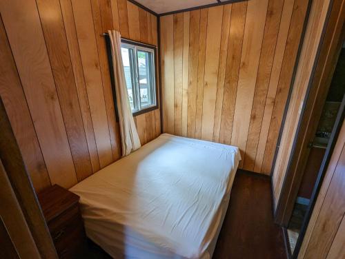 un letto vuoto in una stanza di legno con una finestra di Tiny Wood Cottage 22 a Wasaga Beach