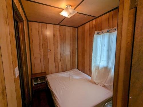 un piccolo letto in una camera in legno con finestra di Tiny Wood Cottage 23 a Wasaga Beach