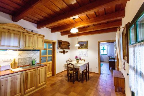 a kitchen with wooden cabinets and a table with chairs at Öreghegyi Apartman in Vindornyalak