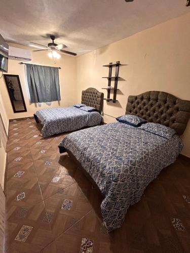 a bedroom with two beds and a cross on the wall at Apartamento Río Nazas Planta Alta in Matamoros