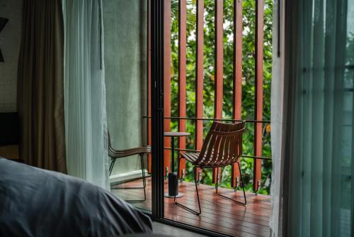 チェンマイにあるThe Hotel Journal Chiangmaiのポーチに椅子が2脚置かれたバルコニー付きの寝室