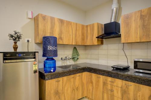 a kitchen with wooden cabinets and a blue bag on the counter at The Lodgers Luxury 1 BHK Serviced Apartment Near Golf Course Road Gurugram in Gurgaon