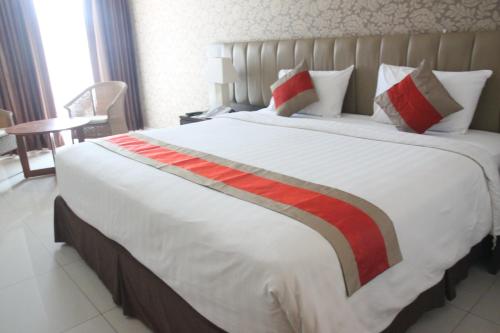 a large white bed with a red stripe on it at Hotel on The Rock in Kupang