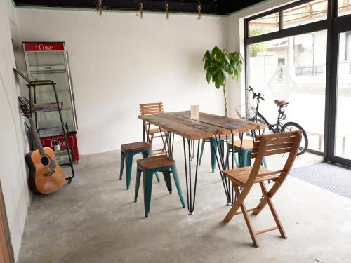 a table and chairs in a room with a guitar at GuestHouse紫雲 -SHIUN- in Toyohama