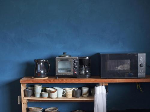 a shelf with a microwave and coffee cups on it at GuestHouse紫雲 -SHIUN- in Toyohama