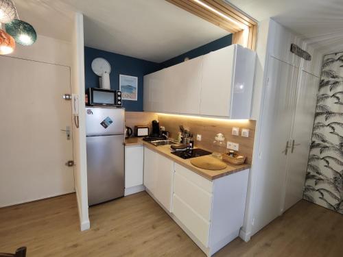  La cuisine est équipée de placards blancs et d'un réfrigérateur. dans l'établissement Appartement Quai Vauban, à Sète