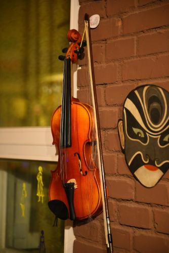 a violin hanging on a wall next to a mask at Xi'an The Facebook Youth Hostel in Xi'an