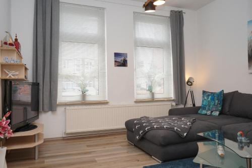 a living room with a couch and two windows at Küstenliebe Cuxhaven 1 in Cuxhaven
