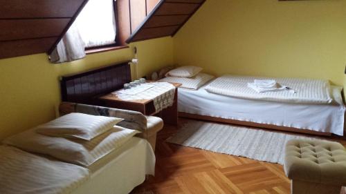 a room with two beds and a table and chairs at Kocsis Panzió és Étterem in Komárom