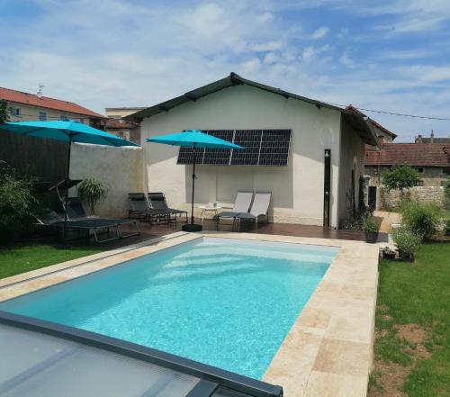 - une piscine en face d'une maison avec des parasols dans l'établissement Chambres d'hôtes les 2 tilleuls, à Figeac