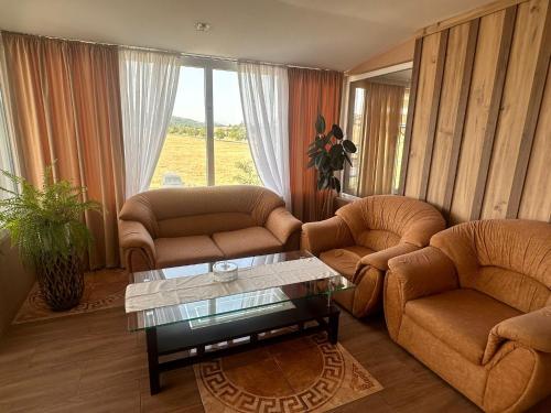 a living room with two couches and a glass table at Hotel Tatul in Momchilgrad