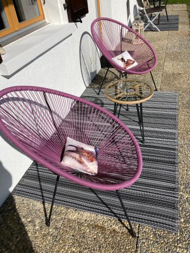 two pink chairs and a table on a patio at Le Lézard et la Grenouille BnB in Ovronnaz