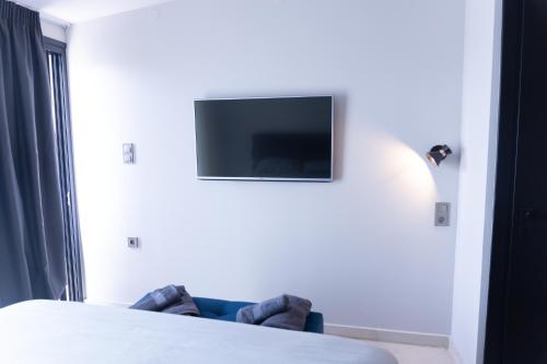 a room with a bed and a tv on the wall at Zafirakis Suites Amaliada in Amaliás
