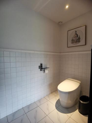 a bathroom with a toilet in a white tiled room at Hangzhou Lanshe hotel in Hangzhou