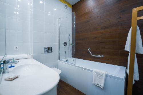 a bathroom with a tub and a toilet and a sink at Kazzhol Park Hotel Almaty in Almaty