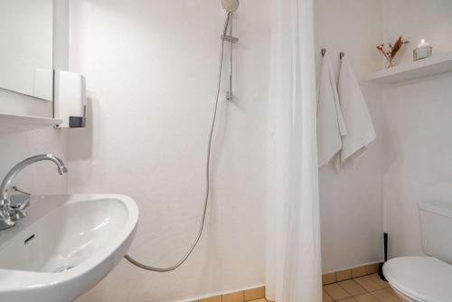 a white bathroom with a shower curtain and a sink at Lindvig - Ferie i naturen in Nymindegab
