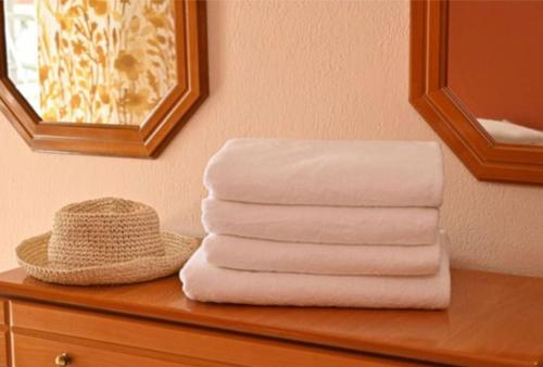 a stack of towels on a dresser with a hat at Appartement entier in Paralia Katerinis