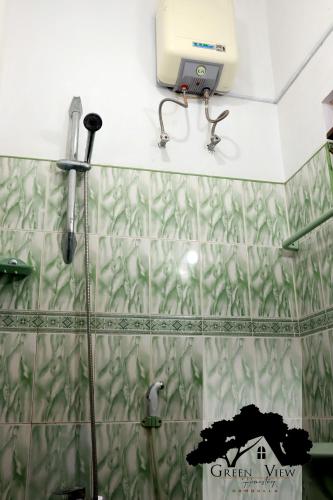 a shower with a green and white tiled wall at Green View in Dambulla