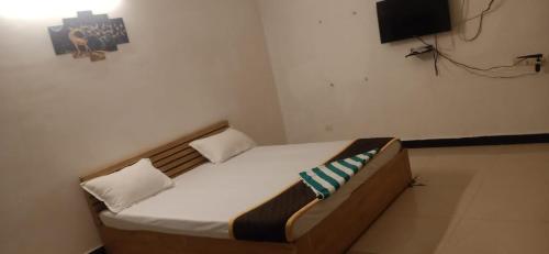 a bed in a room with a tv on the wall at Spacious AC rooms with Swimming Pool Access in Covelong