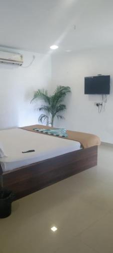 a bed in a room with a plant on the wall at Spacious AC rooms with Swimming Pool Access in Covelong