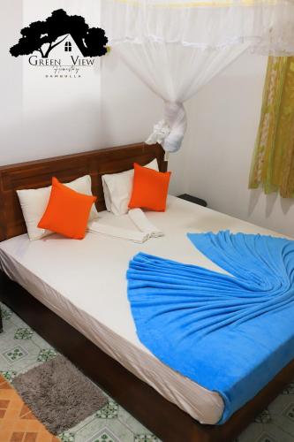 a bed with orange and blue pillows on it at Green View in Dambulla