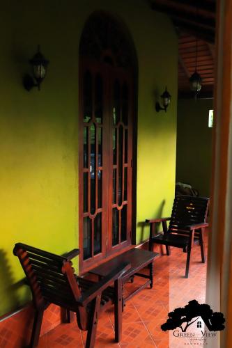two benches sitting in a room with a yellow wall at Green View in Dambulla