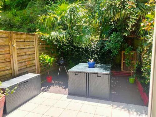 un patio avec une table et un banc dans un jardin dans l'établissement Idéal compromis entre appartement et maison CAMBO, à Cambo-les-Bains