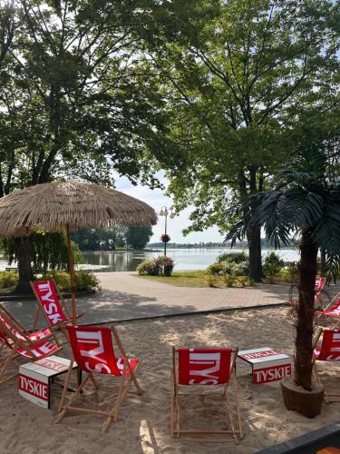 a group of chairs and an umbrella on a beach at Apartament nad Jeziorem Drwęckim w Ostródzie z klimatyzacją in Ostróda