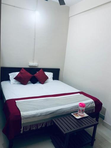 a bedroom with a bed with red pillows and a table at M square residency muttil in Kalpetta