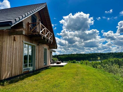 a house on the side of a hill with a green yard at Dabintos slėnis in Sumiliszki
