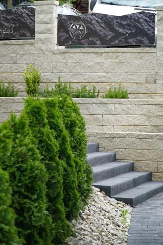 a set of stairs with green bushes in front of a wall at Leśny Wierch luxury spa villas in Bukowina Tatrzańska