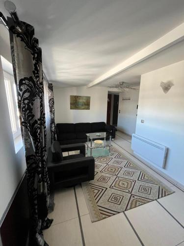 un salon avec un canapé noir et une table dans l'établissement appartement, à Villemomble