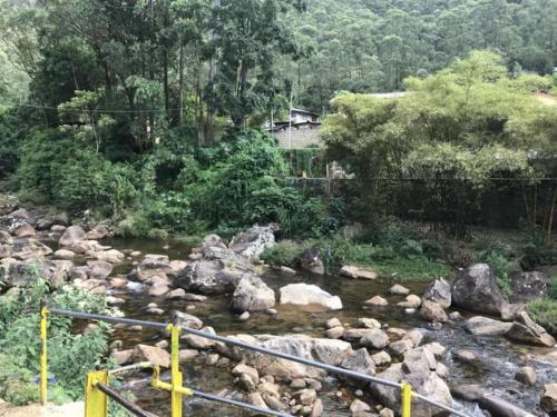 a river with rocks and trees and a bridge at Pure Land Villa in Nallathaniya