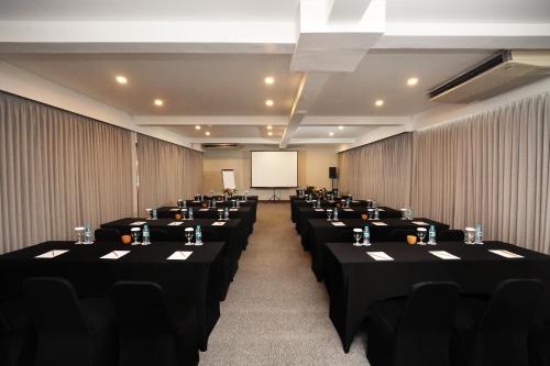 a conference room with tables and chairs and a screen at FuramaXclusive Ocean Beach Seminyak Bali in Legian