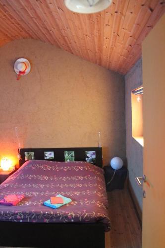 a bedroom with a purple bed with a wooden ceiling at Purple Papillon in Heuvelland