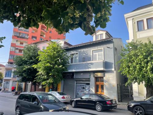 a building on a city street with cars parked in front at Vila Pllaha in Korçë