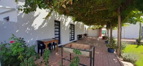 a patio with tables and chairs under a tree at Farmhouse Guestrooms in Calitzdorp