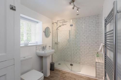 a white bathroom with a shower and a sink at Robins Cottage - Beautiful North Yorkshire Stone Cottage in York