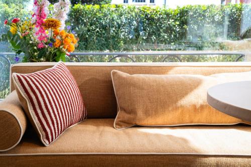 a couch with two pillows and a vase of flowers at Hotel Villa Bonnie in Knokke-Heist