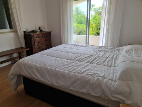 a bedroom with a white bed and a window at Casa dos Arcos in Olhos de Água