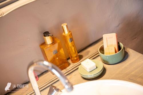 un lavabo de salle de bain avec du savon et d'autres articles sur un comptoir dans l'établissement Chambre d'hôte, à Castex