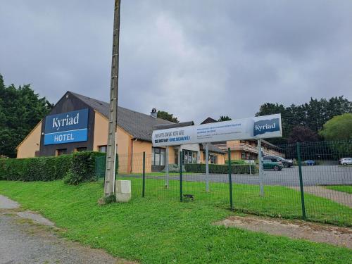un bâtiment avec une enseigne devant lui dans l'établissement KYRIAD HONFLEUR - La Riviere Saint Sauveur, à Honfleur