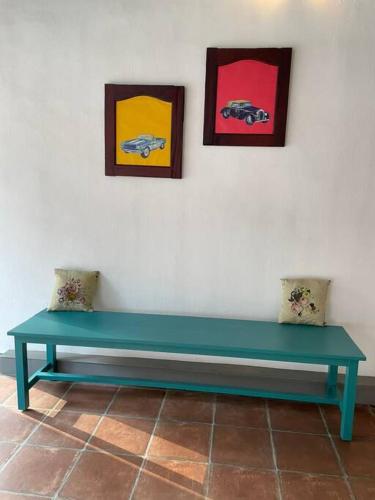 a green bench against a white wall with paintings at Pala Central in Pala