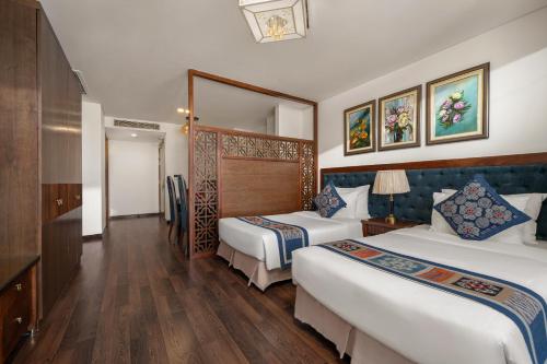 a hotel room with two beds and a mirror at Balcona Hotel Da Nang in Da Nang