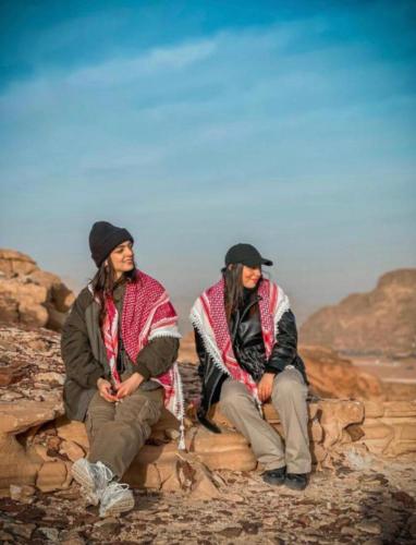 two men sitting on rocks on a mountain at Wadi Rum Luxure desert Camp in Wadi Rum