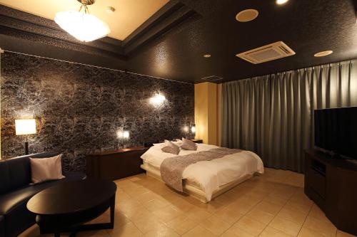a bedroom with a bed and a couch and a tv at ホテルウォーターゲート富山 レジャーホテル 大人用ホテル in Toyama