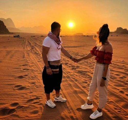 a man and woman standing in the desert holding hands at Wadi Rum Luxure desert Camp in Wadi Rum