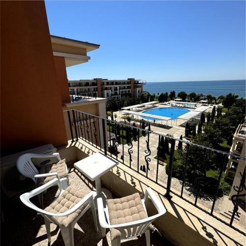 a balcony with two chairs and a swimming pool at Sea view Prestige Fort beach Apartment in Sveti Vlas