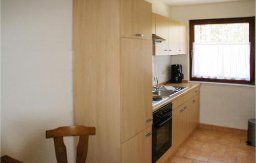 a kitchen with wooden cabinets and a sink and a stove at 2 Bedroom Nice Home In Faßbergheidesee in Oberohe