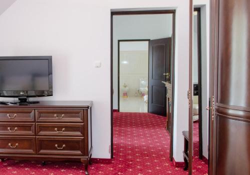 a room with a television and a dresser and a mirror at Hotel Nidzki in Ruciane-Nida